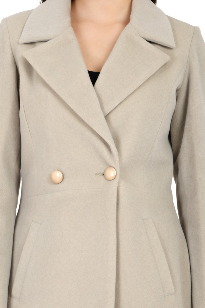 A cropped shot of a woman wearing Trufit’s Double Breasted velvet coat in mint green with a lapel collar, side pockets and a button closure.